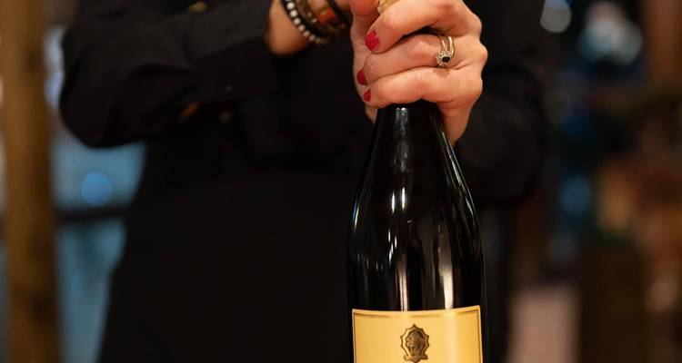 Une personne tenant une bouteille de vin.