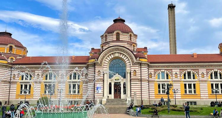 An ornate historical building with a fountain in front.