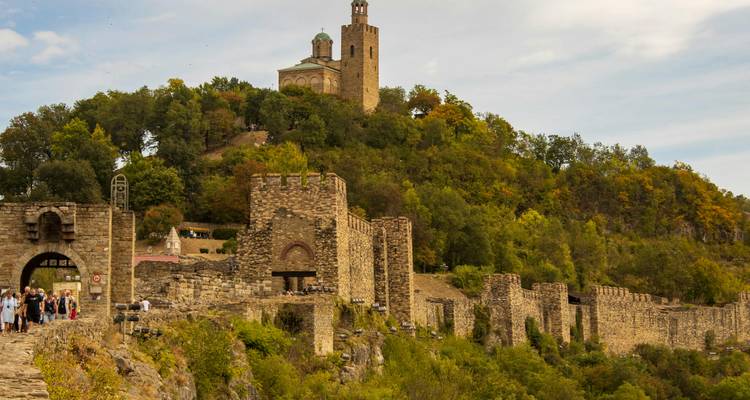 Fortifications historiques au sommet d'une colline avec des gens marchant le long du sentier.