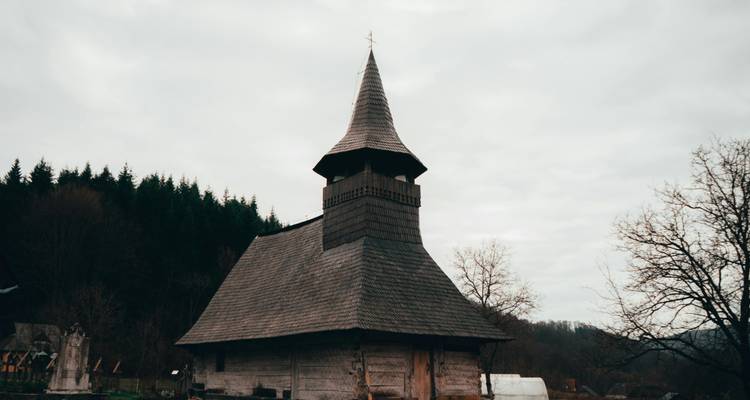 Église en bois contre un ciel couvert avec des arbres en arrière-plan.