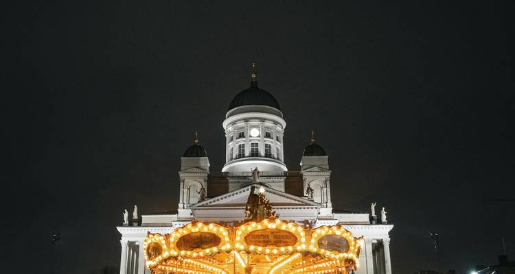 Cathédrale d'Helsinki illuminée la nuit derrière un carrousel lumineux.