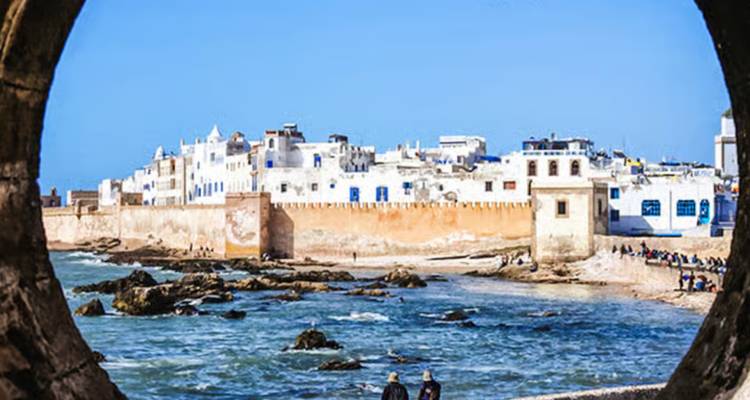Una vista costera de Essaouira con una muralla histórica y olas del océano.