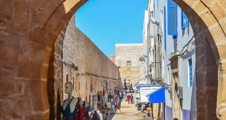 Un mercado con una entrada arqueada en una ciudad histórica, bullendo de gente.