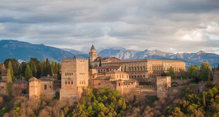 Alhambra in Granada met bergachtige achtergrond tijdens zonsondergang.