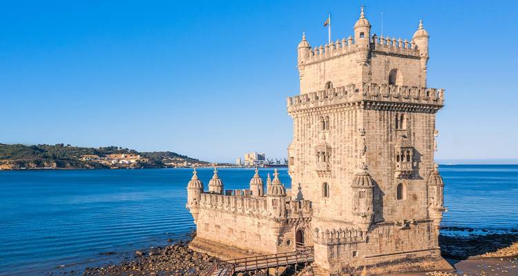 La Tour emblématique de Belém s'élève de l'embouchure du Tage sous un ciel bleu sans nuages.