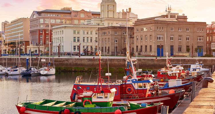 Fishing boats docked in harbor with historical buildings.