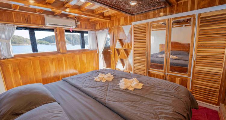 Intérieur d'une cabine avec lit double et mobilier en bois.