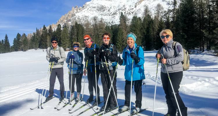 Des skieurs souriants posent pour une photo de groupe devant un décor de pics dramatiques des Dolomites
