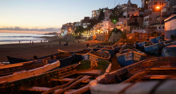 Village côtier avec bateaux et vue sur le coucher de soleil.