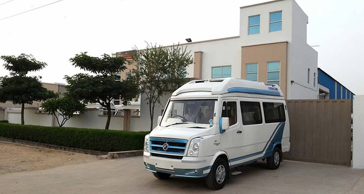 Camionnette blanche garée devant un bâtiment moderne.