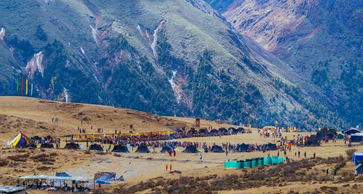 Festivalterrein met menigten en bergen.
