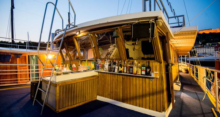 Espace bar extérieur sur un bateau avec un éclairage scénique du soir.