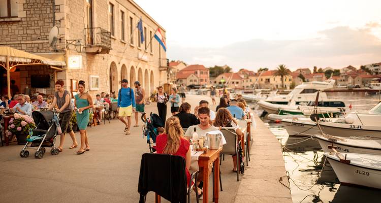 Scène de repas en plein air près du port avec des gens qui savourent leurs repas.