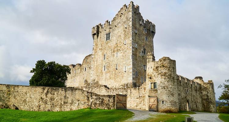 A historical stone castle with a grassy yard.