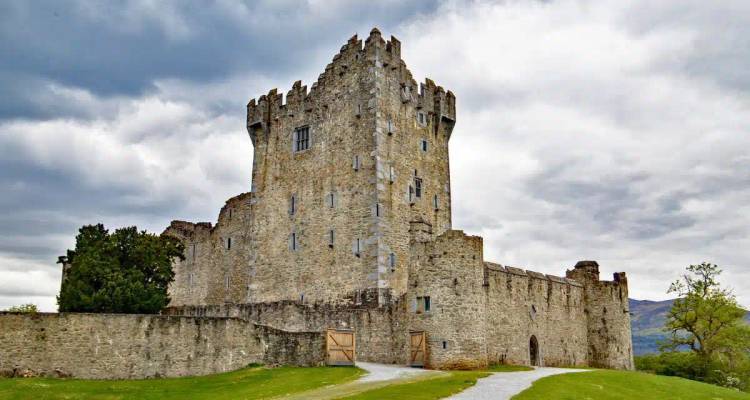 Medieval Ross Castle stands solid against a cloudy sky, its stone walls framed by green lawn.