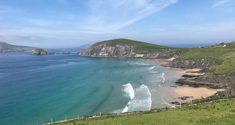 A sweeping crescent beach of golden sand and turquoise water backed by green headlands.
