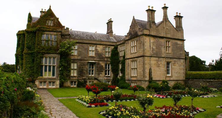 Une grande maison historique entourée de jardins.