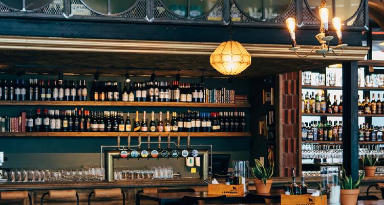 Bar mit Regalen voller Flaschen und hängenden Lichtern.