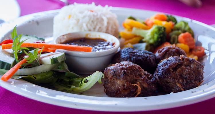 Teller mit Reis, Fleisch und Gemüse auf einem Tisch.