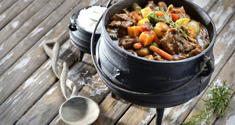 Topf mit Gemüseeintopf neben einem kleinen Topf mit Reis.