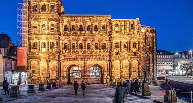 Mensen die 's nachts langs een verlicht historisch gebouw lopen.