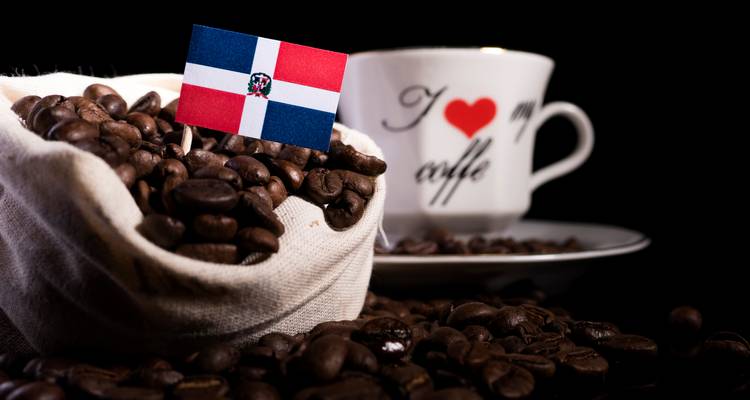 Grains de café dans un sac avec le drapeau dominicain, tasse en arrière-plan.