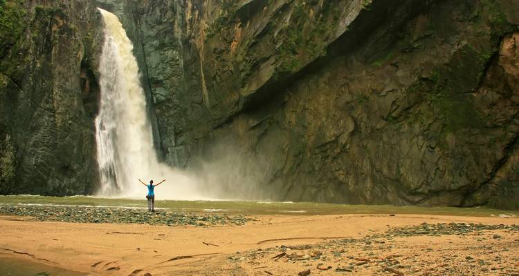 Personne debout près d'une grande cascade.