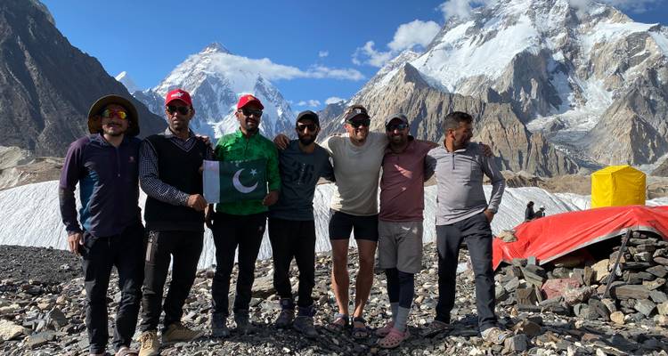 Un grupo de excursionistas posando con una bandera en las montañas.