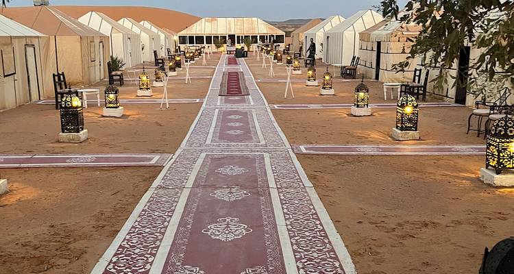 Desert camp with tents and decorative lanterns in the sand.