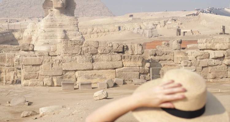 Vue partielle d'une personne devant le Sphinx et une pyramide.