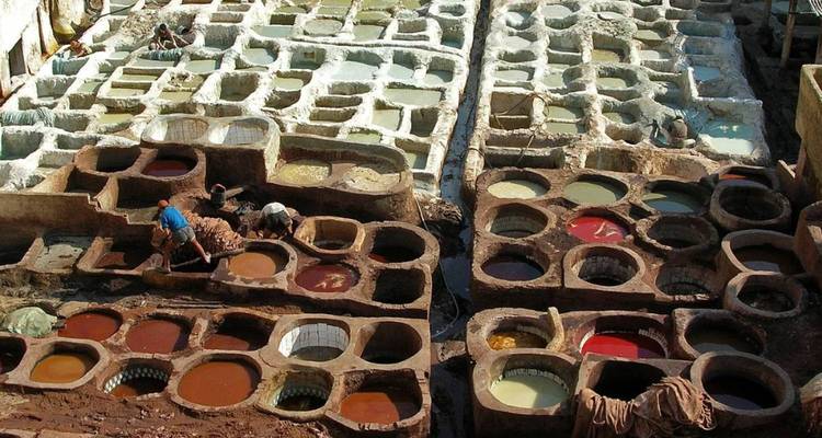 Curtiembres tradicionales con piscinas de teñido coloridas y gente trabajando.