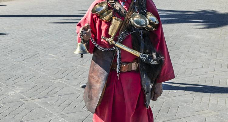 Une personne vêtue de façon traditionnelle avec des ornements métalliques dans un environnement urbain.