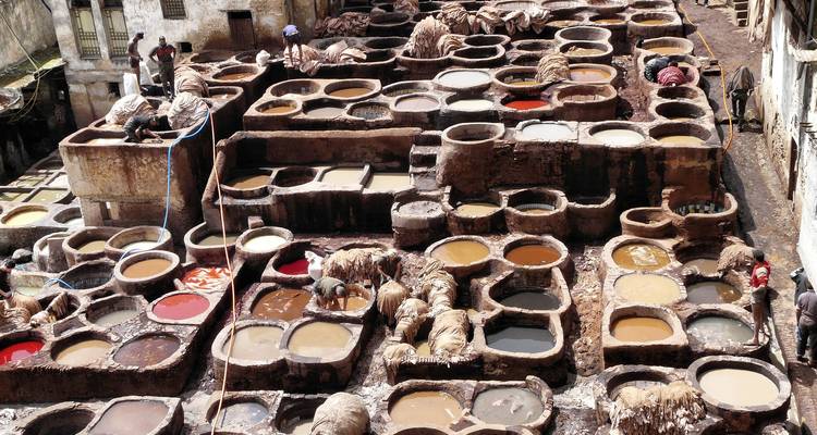 Un aperçu des cuves de teinture traditionnelles avec des ouvriers à l'intérieur.