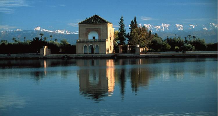 Un pavillon se reflétant sur un lac avec des montagnes en arrière-plan.