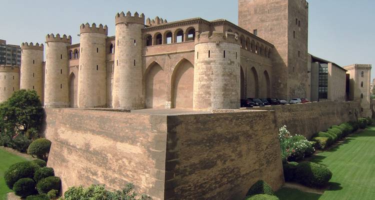 Palacio de la Aljafería en Zaragoza con exuberantes jardines verdes.