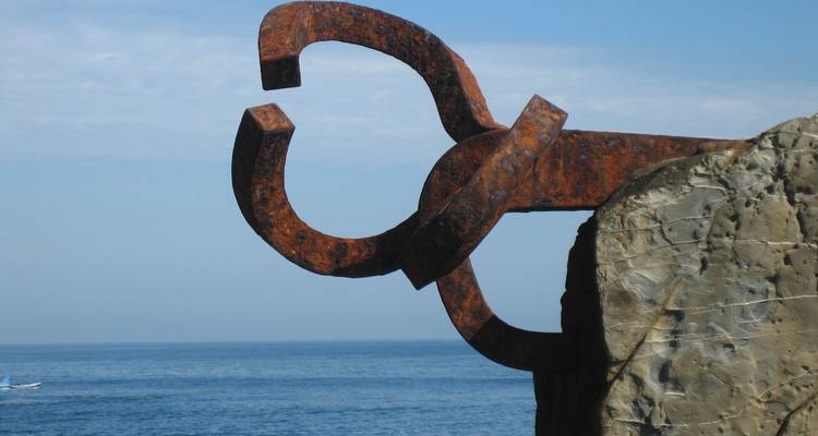 Escultura metálica rústica con vista al océano en España.