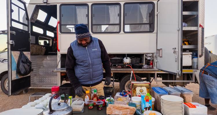 Der Küchenchef der Overland-Tour richtet eine Außenküche zum Frühstück neben einem speziell ausgestatteten Lastwagen mit Vorräten ein.