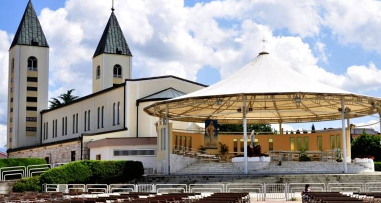 Gran iglesia con torres gemelas y un escenario al aire libre.