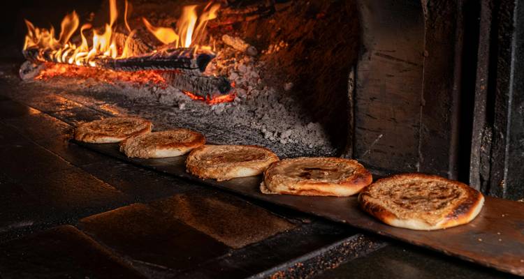 Traditionelle Fladenbrote, die auf einem Holzschaufel in einem Holzfeuer-Ofen mit glühenden Gluten gebacken werden.