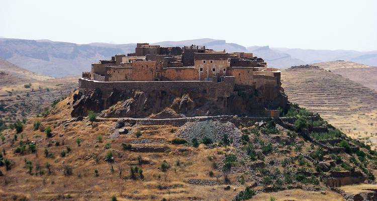 Village isolé sur une colline avec des bâtiments en pierre.