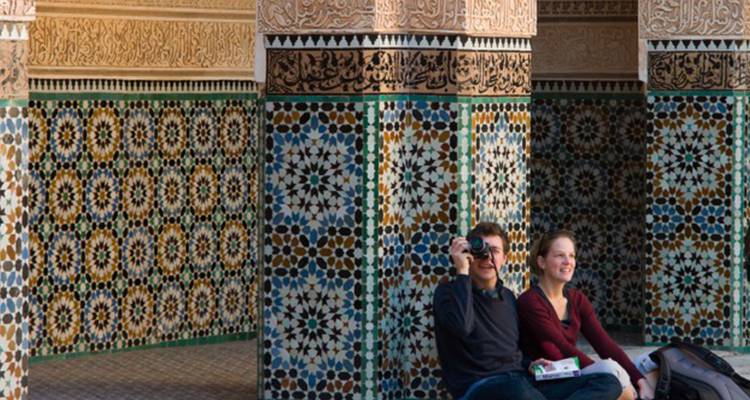 Deux touristes assis dans une cour carrelée avec un appareil photo.