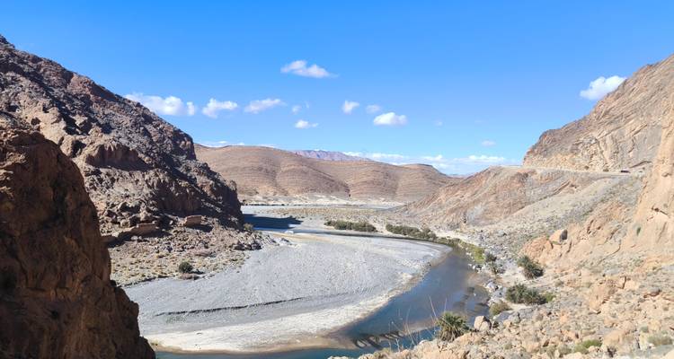 Vue panoramique d'une vallée fluviale rocheuse sous un ciel bleu.