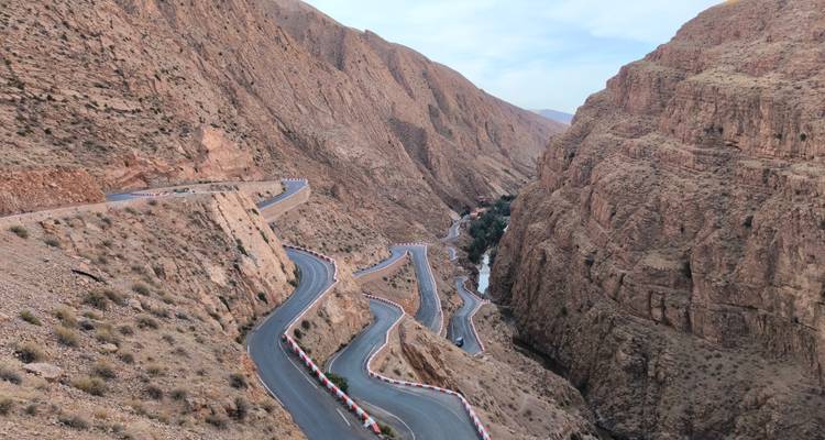 Une route sinueuse à travers un paysage de gorges rocheuses avec une rivière en contrebas.