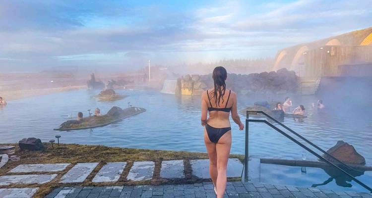 Persona en traje de baño junto a una piscina geotermal con vapor.