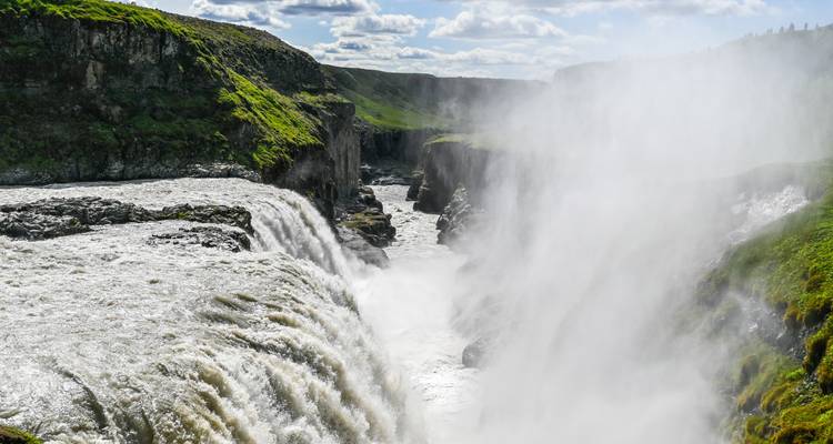 Poderosa cascada con neblina y un paisaje verde.