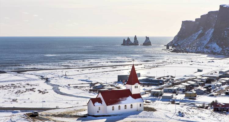 Vista de una iglesia y pueblo cerca de la costa con acantilados.