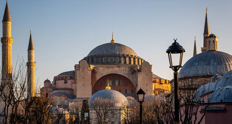 Vista exterior de icónica mezquita con cúpula durante la hora dorada, capturada con una farola en primer plano.