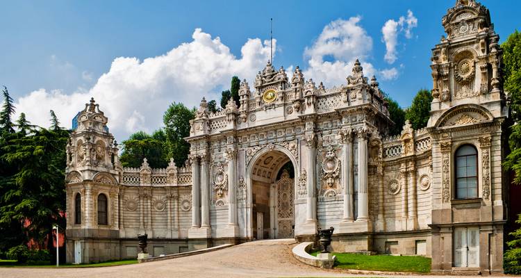 Gran puerta de palacio con intrincados detalles arquitectónicos bajo un cielo azul brillante.