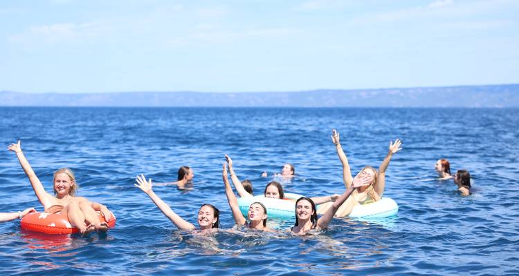Groep mensen die genieten van zwemmen en drijven in de zee.