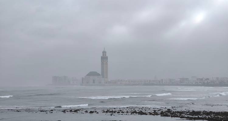 Een ver zicht op een moskee aan de overkant van de zee onder een bewolkte hemel.